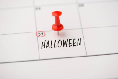 Etiket tarihi 31 Ekim 'in üstünde cadılar bayramı ve takvim arka planında izole edilmiş kırmızı iğne