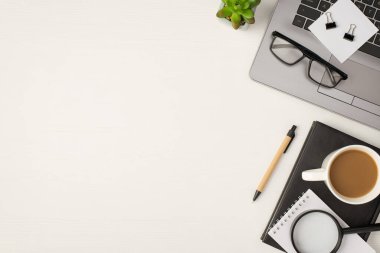 Gözlük fotoğrafının üst görüntüsü kağıt yapıştırıcı raptiyeleri dizüstü bilgisayarın çiçek saksısı çay fincanı ve büyüteçler üzerinde izole edilmiş beyaz ahşap masa zemininde