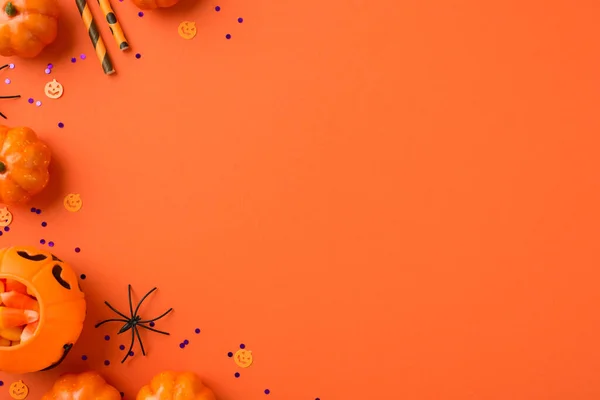 キャンディコーンストローのスパイダーと紫色のスパンコールを持つハロウィンの装飾カボチャのバスケットのトップビューの写真は 空のスペースを持つ孤立オレンジの背景に — ストック写真