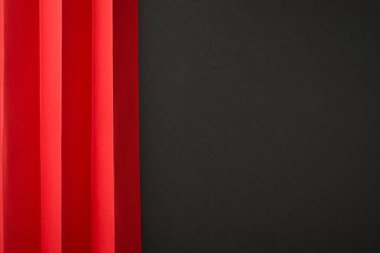 İzole edilmiş siyah arkaplan üzerinde dikey kıvrımlı kırmızı kağıt kağıdın sağ tarafında boş alan ile en üstteki görünüm fotoğrafı