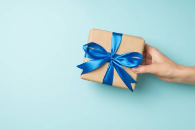 En üstteki fotoğrafta kadın eli, el sanatları için kağıt hediye kutusu veriyor. Üzerinde parlak mavi saten bir kurdele var.