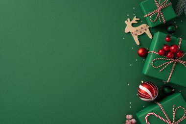 Yeşil tatil sahnesinde hediyeler, tahta ren geyikleri ve kırmızı ve beyaz aksanlar Noel ve yeni yıl kutlamalarının neşeli havasını yansıtıyor.