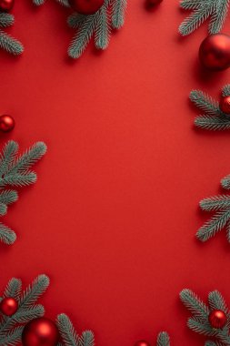 Çam dallarının süslendiği dikey kırmızı arka plan Noel kutlamaları ve kutlamalar için sıcak mevsimlik ortam yaratıyor.