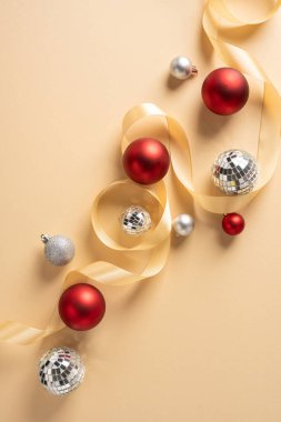 Kırmızı ve gümüş süslemelerin dikey dizilişi. Sıcak bej arkaplanda soluk renkli kurdeleyle sarmalanmış.