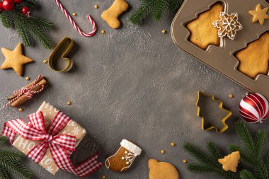 Üst düzey bir tatil düzenlemesinde kurabiyeler, bir fırın tepsisi, paketlenmiş hediye, şeker kamışı ve çam dalları, Noel ve yeni yıl için şenlik neşesi ve mevsimlik ruh iletilir.