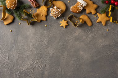 Krema ve dekoratif şekillerle süslenmiş çeşitli zencefilli kurabiye ve kurabiyeler, Noel ve yeni yıl neşesini ılık baharatlar, parlak renkler ve tatil cazibesiyle anımsatarak şenlikli bir sınır boyunca otururlar.