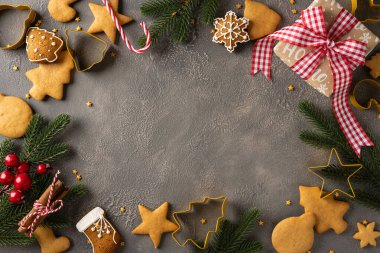 Kurabiye şekilleri, şeker kamışları, paketlenmiş hediyeler, çam dalları, kırmızı böğürtlenler ve şenlikli dekorasyonların yer aldığı sıcak bir Noel sahnesi.