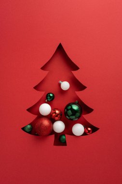 Kırmızı, yeşil ve beyaz süslemelerle süslenmiş kırmızı bir Noel ağacı Noel ve yeni yıl kutlamaları ve mevsimsel selamlaşmalar için mükemmel bir bayram sahnesi oluşturuyor.