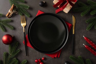 Noel ziyafeti sofrası. Siyah tabak altın çatal bıçak takımı. Kırmızı peçete.