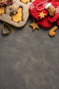 Kurabiye hamuru, kesme şekilli kek kutusu, zencefilli kurabiye yıldızları, kırmızı fırın eldiveni ve baston şekerlerin yer aldığı dikey bir festival sahnesi, bayram pişirme, sıcaklık ve mevsimsel kutlamaları yakalıyor.