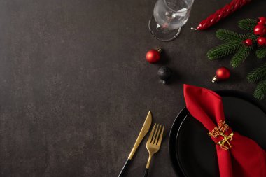 Noel ve Yeni Yıl için en iyi manzara masası kırmızı peçete, altın çatal bıçak, siyah tabak, cam süs ve bayram kutlamaları için yeşil aksanlı.