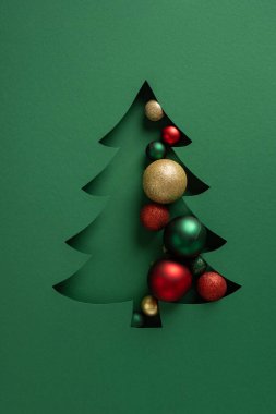 Yeşil kartta altın, kırmızı ve yeşil süslemelerle dolu biçimlendirilmiş bir Noel ağacı kesimi Noel ve Yeni Yıl kutlamaları için neşeli ve modern bir görünüm yaratıyor