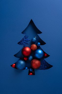 Dikey stilize edilmiş kırmızı ve mavi süslemeli mavi Noel ağacı Noel ve yeni yıl kutlamaları için uygun bir bayram kartı tasarımı yaratır. Modern, cesur ve dekoratif.
