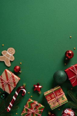 Dikey yeşil çerçeve paketlenmiş hediyeler, şeker kamışı, zencefilli ekmek adam, süsler ve Noel ve yeni yıl için hazır olan şenlikli dekor