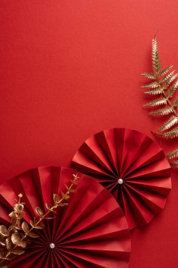 Canlı bir dikey kırmızı sahne arkası vitrinleri, metal eğreltiotu aksanıyla eşleştirilmiş zengin altın tonlarında kağıt yelpaze süslemeleri katlıyordu.