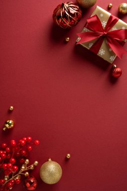 Noel hediyesi, kırmızı kurdele, altın ve kırmızı süslemeler ve şenlikli böğürtlenlerle dolu dikey bir tatil sahnesi Noel ve yeni yıl için mükemmel bir zemin hazırlıyor.