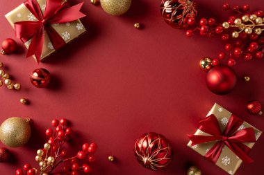 Zengin bir kırmızı tatil düzeninde hediyeler, parlak süsler, böğürtlenler ve altın aksanlar, Noel ve yeni yıl kutlamaları ve mevsimsel selamlaşmalar için şenlikli bir ortam yaratıyor.