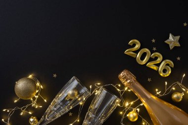 Şampanyalı şık bir yeni yıl sahnesi, iki flütlü bardak, altın süsler ve peri ışıkları bayram ve yıl sonu kutlamaları için şenlikli bir ortam yaratıyor.