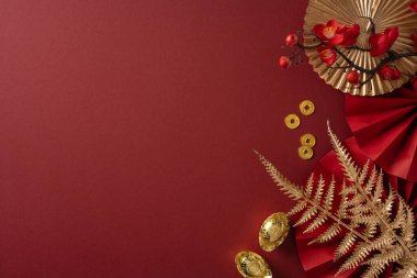 Altın aksanlı canlı kırmızı zemin, fenerler, sikkeler, eğrelti otu yaprakları, kurdeleler ve dekoratif taç yapraklarının yer aldığı, şans, refah ve şenlik cazibesini çağrıştıran bir Çin Yeni Yıl kutlamasını yakalıyor.