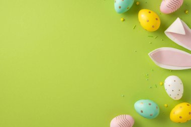 Canlı yeşil bir zemin üzerinde renkli yumurtalar ve pastel tavşan kulaklarıyla canlı Paskalya sahnesi ilkbahar için kutlama, yenilenme ve neşeli selamlaşmaları çağrıştırıyor.