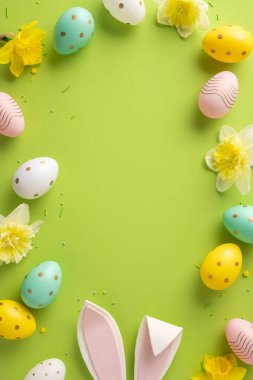 Pastel yumurtalar, sarı çiçekler ve mevsimsel selamlaşmalar ve bahar kutlamaları için parlak yeşil bir arkaplan içeren hareketli dikey Paskalya temalı kompozisyon