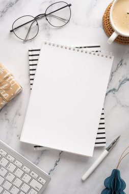 Bir defter, bardaklar, kahve ve klavye ile bir masa sahnesi. Modern bir çalışma alanında Noel ve yeni yıl kutlamaları ve bayram planlaması öneriliyor.