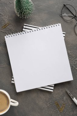 Çizgili çarşaflara katlanmış boş bir defter, bir kahve fincanı, bardaklar ve zarif Noel ve yeni yıl aksanları ile şık bir çalışma alanı sahnesi tatil planlama ve selamlamaya hazır.