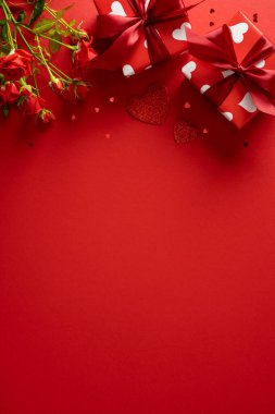 Kırmızı dikey arkaplanda kalp desenleri, hediye kutuları ve bir buket gül var. Romantik bir sevgililer günü havası yaratıyor. Kutlama kartları, romantik kampanyalar, hediyeler ve aşk temalı terfiler için mükemmel.