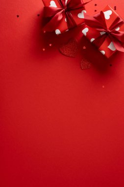 Kırmızı dikey zemin, iki hediye kutusu, kurdeleler ve beyaz kalp desenleri. Sevgililer Günü tebrikleri, romantizm, hediye fikirleri, aşk anları ve şenlikli kutlama görüntüleri için mükemmel.