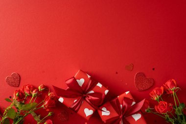 Canlı bir sevgililer günü sahnesinde kırmızı güller, kalp desenli hediye kutuları, zengin kurdele kurdeleleri ve romantik bir kutlama için ayarlanmış şaşaalı aksanlar, aşk, bağlılık ve bayram hediyeleri yer alıyor.