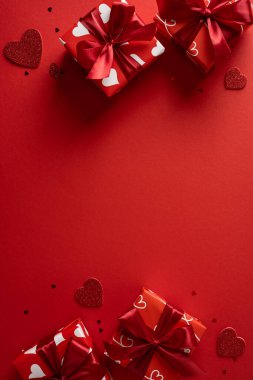 Canlı dikey kırmızı arka plan özellikleri hediye kutularını saten kurdelelerle ve dağınık kalp şekilleriyle sarmış, romantik bir sevgililer günü havasını iletiyor hediye, aşk ve kutlama temaları için mükemmel.