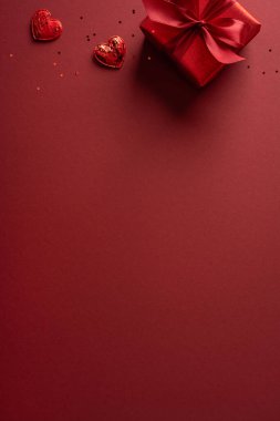 Canlı dikey kırmızı arka plan gösterileri yaylı ve dağınık dekorasyonlu bir hediye, romantizm, aşk ve sevgililer günü kutlamaları ve hediye mesajları için uygun.