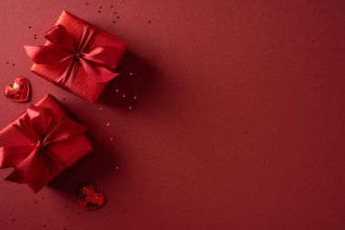 Kırmızı arka planda iki hediye kutusu, papyonlar ve küçük kalpler romantizm ve sevgililer günü havası, tebrik kartları, promosyonlar ve mevsimsel aşk kampanyaları için mükemmel.