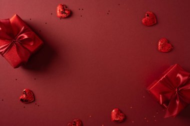 Kırmızı hediye kutuları ve kalp şekillerinin olduğu romantik sahne zengin kırmızı bir zemin üzerine dağılmış, aşk için mükemmel, hediyeler ve sevgililer günü teması