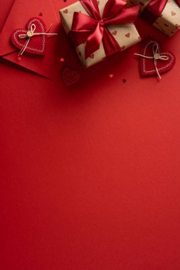 Sarılı hediyeler, kurdeleler ve kalp aksanıyla canlı, dikey kırmızı arka plan Sevgililer Günü kutlamaları ve hediye fikirleri için romantik, şenlikli bir ortam yaratır.