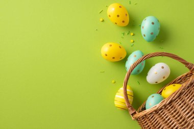 Renkli Paskalya yumurtaları hasır bir sepetten canlı bir limon arkaplanına dökülüyor. Pastel renkler, neşe saçan serpiştirmeler ve neşeli bir bahar sahnesi. Kutlama kartları, tatiller ve kutlamalar için mükemmel.