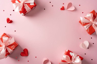 Sevgililer günü temalı kırmızı hediye kutuları ve yumuşak pembe arka planı olan kurdeleler ve kalp şekilleriyle süslenmiş bir sahne. Romantizm, hediye, aşk ve şenlikli Şubat kutlamaları için uygundur.