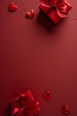Kırmızı dikey arka plan dekoru hediye kutuları, kurdeleler ve kalp çikolataları romantik bir sevgililer günü havası yaratır, tebrik kartları, hediye kampanyaları ve şenlik promosyonları için ideal.