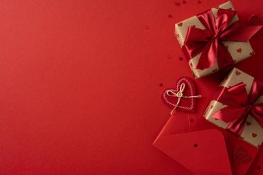 Sarılı hediyeler, kalp şeklinde bir etiket, kırmızı bir zarf ve aşkın, sıcaklığın ve kutlamaların anlatıldığı kırmızı bir arkaplanda şenlik kurdeleleri içeren romantik bir sevgililer günü sahnesi.