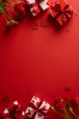 Sevgililer Günü tebrikleri ve aşk mesajları için mükemmel kırmızı bir zemin üzerinde hediye kutuları, kırmızı güller ve parlak kalpler içeren romantik dikey sahne