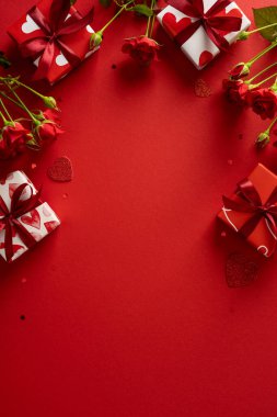 Kırmızı güllerin ve kalp motifleriyle dolu hediye kutularının olduğu romantik dikey sahne koyu kırmızı arka planda sevgi, kutlama ve kartlar ve terfiler için uygun sevgililer günü tebriklerini iletiyor.