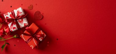 Kırmızı pankart üzerinde romantik sevgililer günü hediyeleri sunan kalp hediyeleri ve kurdeleler, tebrik kartları, tanıtım resimleri ve mevsimlik stok fotoğrafları için ideal bir ortam yaratıyor.