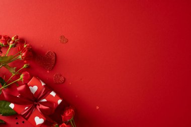 Canlı bir kırmızı arka plan, kart, reklam ve kampanyalar için uygun bir kutlama, romantizm, sıcaklık ve taze güllerle sarılı bir sevgililer günü hediye kutusunu ön plana çıkarıyor.