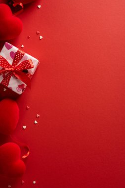 Romantik dikey sevgililer günü sahnesinde kalp motifleri, kırmızı kurdele ve dağınık küçük kalpler bulunur. Romantizm, aşk, kutlama ve hediye fikirleri için idealdir.