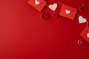 Zarflar, kağıt kalp kesikleri ve ip süslemeleri, romantizm, şefkat ve şenlikli selamlama içeren canlı kırmızı bir Sevgililer Günü temalı bir set.