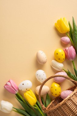 Parlak dikey Paskalya sahnesinde lale çiçekleri, pastel yumurtalar ve kadife arka planda hasır bir sepet, tebrik kartları, bahar promosyonları ve mevsimlik dekorlar için ideal.
