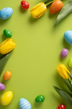 Parlak dikey Paskalya sahnesi, lale çiçekleri ve limon arkaplanı etrafına dizilmiş renkli yumurta süslemeleri. Tebrik kartları, bahar kampanyaları ve mevsimlik promosyonlar için mükemmel.