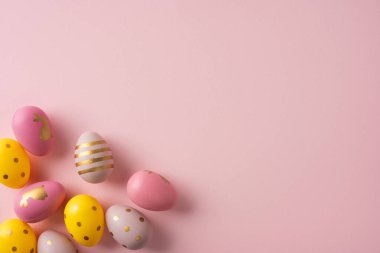 Yumuşak pembe arkaplanlı renkli pastel yumurtalar sıcak Paskalya kutlamalarını ve mevsimlik kartlar için neşeli selamları çağrıştırır.