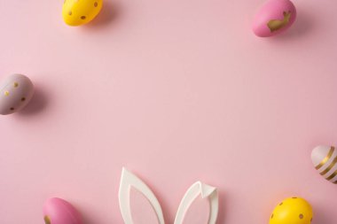 Pastel Paskalya yumurtaları ve tavşan kulak aksanı yumuşak pembe bir zemine oturup Paskalya kutlamaları ve bahar kutlamaları için mükemmel bir festival sahnesi yaratıyor.