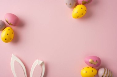 Paskalya yumurtaları ve tavşan kulakları yumuşak pembe bir fon üzerinde neşeli bir ruh hali, sıcaklık ve bahar kutlamaları ve neşeli anlar için bir karşılama iletin.